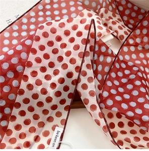 Gros plan d'un foulard en mousseline de soie à pois rouges et blancs avec coutures fines