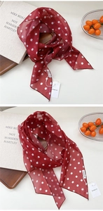Vue détaillée du foulard en soie rouge à pois fins drapé sur un plateau en bois