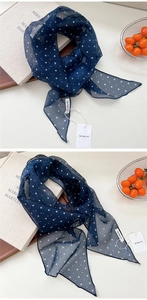 Détail d'un foulard en soie bleu marine à pois avec étiquette sur fond de style de vie
