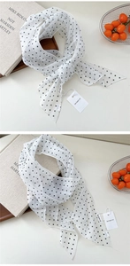 Détail d'un foulard en soie blanche à pois noirs sur fond d'accessoires de style