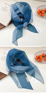 Détail d'un foulard en soie à pois bleus avec étiquette et bordures finement cousues