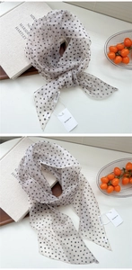 Détail d'un foulard en mousseline à pois légers avec étiquettes sur des livres en lin