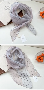 Détail d'un foulard fin en soie à pois avec des tons lavande clairs et une étiquette de marque