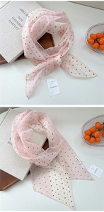 Gros plan d'un foulard en soie rose à pois avec étiquette sur fond minimaliste