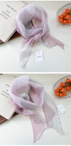 Détail d'un foulard en soie à pois dégradé rose avec étiquettes sur bureau moderne