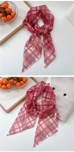 Macro detail of red and blue checkered mesh scarf with brand label on white surface