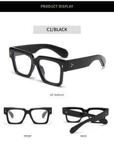 Detail view of glossy black square eyeglass frames with gold rivet accents and wide temples
