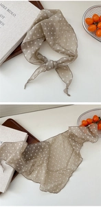 Detailed view of polka dot neck scarf showing smooth translucent fabric and tied styling