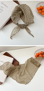 Close-up of semi-transparent polka dot silk scarf in olive green and khaki with fine edges