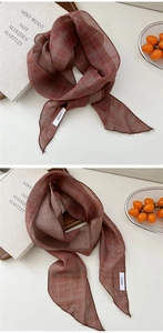 Détail d'une écharpe en lin à carreaux terre cuite avec texture naturelle et tissu léger