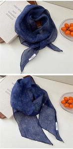 Détail d'une écharpe en lin bleu marine à rayures et motifs floraux, texture légère