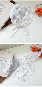 Detailed close-up of a floral chiffon scarf with orange and blue patterns on white fabric