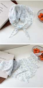 Close-up of thin floral chiffon neck scarf with blue flowers and wavy stitched edges