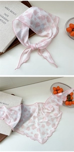 Close-up of light pink floral silk scarf showing delicate red stitched edges and tulip print
