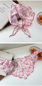 Detail of red floral pattern on white silk scarf with delicate hemmed edge finishing
