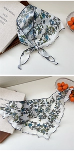 Detailed close-up of floral silk scarf with delicate navy blue overlock stitched edges