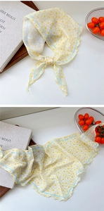 Detail of yellow floral triangle scarf with blue border on a rustic wooden background
