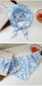 Detail of light blue floral triangle scarf showing delicate rolled edges and chiffon fabric