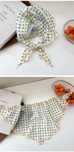 Detail of floral triangle neck scarf with yellow trim and green flower pattern