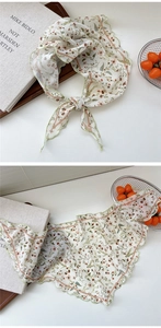 Close-up of lightweight floral triangle scarf with delicate green wavy edges and patterns
