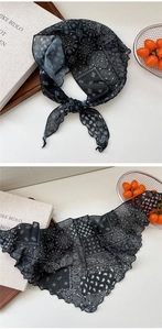 Detail of a thin black floral neck scarf with paisley pattern and wavy scalloped edges