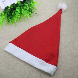 Top view of red felt Christmas hat with white pompom on beige fabric surface