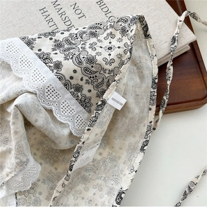 Close-up of beige paisley scarf with white lace trim and 100% viscose fabric texture