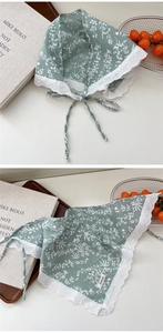 Close-up of green floral cotton linen scarf with white lace trim and branding label