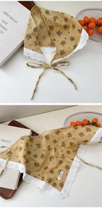 Detail of yellow floral cotton linen scarf featuring white heart lace trim and tie strings
