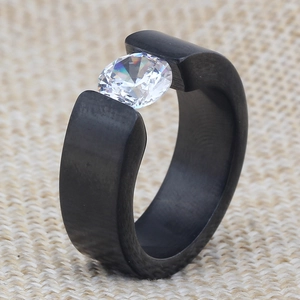 Macro shot of 8mm black band ring with tension-set round diamond on linen texture