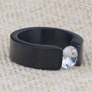 Macro view of 8mm black brushed stainless steel ring with a tension-set clear gemstone