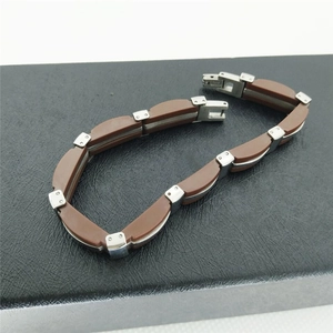 Detailed close-up of a brown leather and silver stainless steel link bracelet on a box