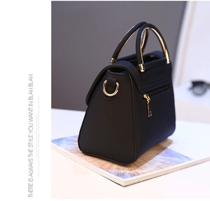 Detail of black lychee grain leather bag featuring a gold metal circular handle and hardware