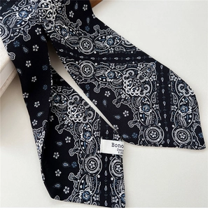 Close-up of black silk scarf with blue paisley pattern and white woven brand label