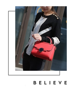 Detail of red textured leather handbag with gold circular twist lock on a female model