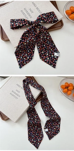Detail of floral skinny scarf with pointed ends and vintage patterns on wooden tray