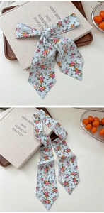 Detailed close-up of light blue floral skinny silk scarf showing pointed ends and fabric texture