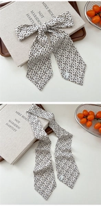 Detail of leopard print skinny silk scarf tied in a bow on a rustic wooden tray