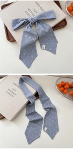 Detail of light blue floral silk scarf tied in a bow on a rustic wooden tray