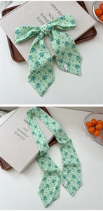 Detail of light green floral silk scarf tied as a bow with chiffon texture for hair or bags