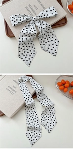 Detailed view of polka dot silk scarf tied as a bow on a minimalist aesthetic background
