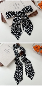 Close-up of black and white spotted silk scarf tied in a bow on a wooden tray