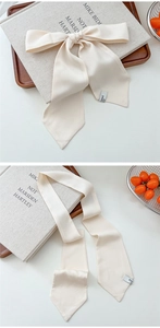 Cream satin hair ribbon tied in a bow on a book showing silk texture and pointed ends