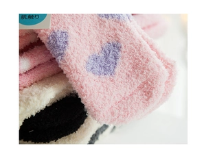 Close-up of soft coral fleece texture and heart patterns on thick winter socks