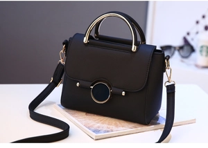 Detail of black pebbled leather bag with gold circular twist lock and metal handle