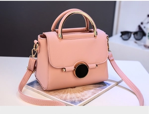 Detail of pink lychee leather bag with golden ring handle and black round lock