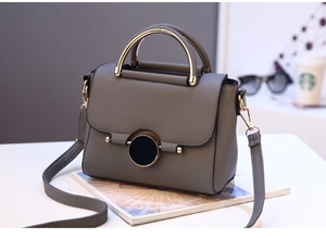 Close-up of a grey lychee pattern leather handbag with golden round lock on a magazine