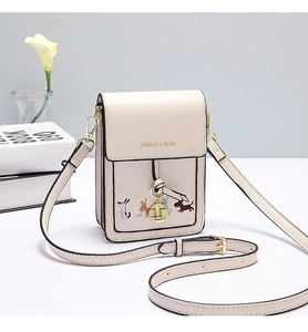 Detailed embroidery of colorful dogs on a beige leather shoulder bag with gold hardware