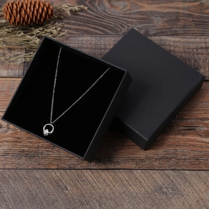 Collier trèfle argenté dans un coffret cadeau noir mat sur fond de bois de style vintage