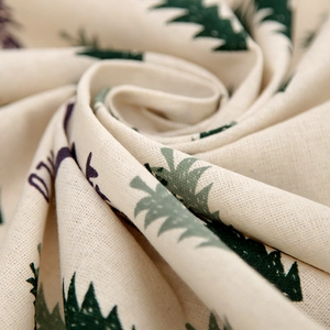 Close-up of beige linen fabric texture with green Christmas tree and deer prints